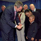 March of Dimes Ambassador Justin Lamar Washington donates one dollar to President Bush as his contribution to assist Afghan children.