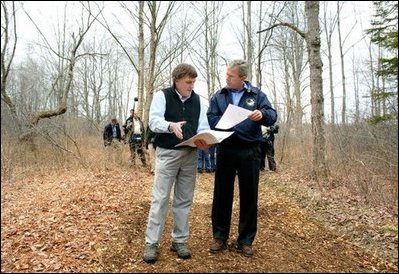 President George W. Bush looks over maps of the Wells National Estuarine Research Reserve with Manager Paul Dest in Wells, Maine, Thursday, April 22, 2004.
