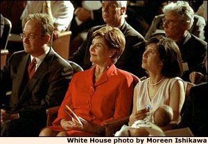 Georgetown University President John J. DeGioia, Laura Bush, and Theresa DeGioia, who is holding young J.T. DeGioia, listen to speakers at the White House Summit on Early Childhood Cognitive Development at Georgetown University, July 26-27, 2001. White House photo by Moreen Ishikawa.
