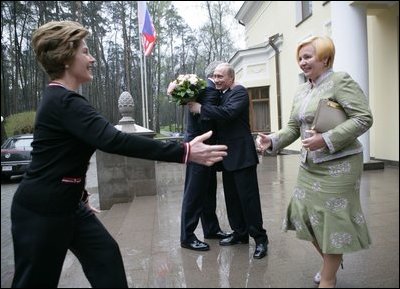 President George W. Bush and Russia President Vladimir Putin embrace in the background as Mrs. Bush reaches out to Lyudmila Putina, Russia's first lady, as the Bushes arrived Sunday, May 8, 2005, at the Putin residence shortly after their arrival in Moscow.