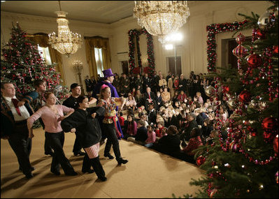 President George W. Bush and Mrs. Laura Bush sit with children of deployed U.S. military personnel and watch a performance of "Willy Wonka" by members of The Kennedy Center Education Department in the East Room Monday, Dec. 4, 2006.