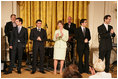 Mrs. Laura Bush stands with members of the cast from the Tony award-winning musical Jersey Boys perform during a luncheon for Senate Spouses in the East Room Monday, June 12, 2006.