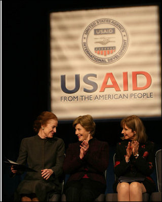 Mrs. Laura Bush applauds as she's joined on stage by Ms. Henrietta Fore, left, Administrator of the U.S. Agency for International Development and Director of the United States Foreign Assistance, and Ambassador Paul Dobriansky, Under Secretary of State for Democracy and Global Affairs, for the USAID Celebration of International Women's Day Friday, March 7, 2008, at the Ronald Reagan Building in Washington, D.C.
