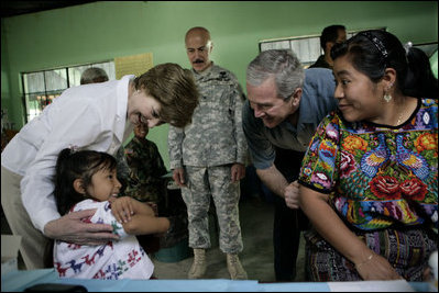 President George W. Bush and Mrs. Laura Bush play with a young girl during a visit Monday, March 12, 2007, to the Carlos Emilio Leonardo School in Santata Cruz Balanya, Guatemala. The couple visited a medical readiness and training exercise site at the school. White House photo by Eric Draper