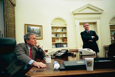 Chief of Staff Andy Card stands by as President George W. Bush talks with World Leaders and members of Congress after the capture of Saddam Hussein in the Oval Office Dec. 14, 2003. 