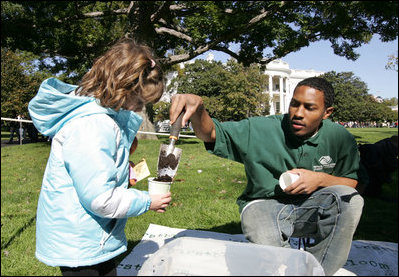 A volunteer helps a youngster with her First Bloom, seed-planting Sunday, Oct. 19, 2008, during the Fall Garden Tour of the White House.