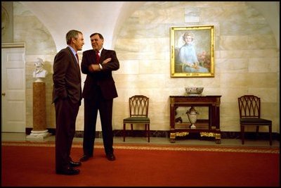 Before taking a photo with Hispanic members of his staff as part of the Cinco de Mayo celebrations, President George W. Bush speaks with Secretary for Housing and Urban Development Mel Martinez in the downstairs corridor May 3, 2002. 