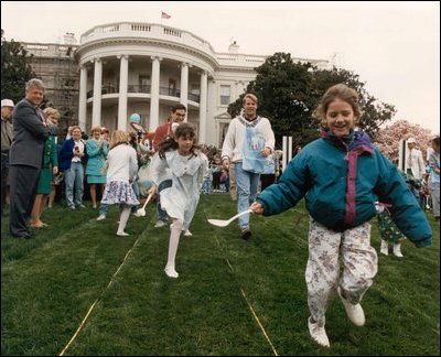 President Clinton and First Lady Hillary Clinton watch children's egg roll races during the 1993 Easter Egg Roll. Mrs. Clinton expanded the egg roll to the Ellipse to include additional activities for both children and adult attendees.
