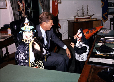 President John Kennedy meets with his halloween-clad children, Caroline and John, Jr., in the Oval Office. 