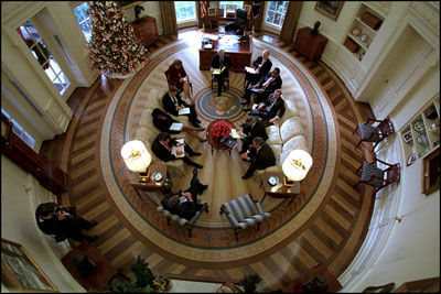 President George W. Bush hosts a meeting on Dec. 20, 2001, with senior advisers in the newly-renovated Oval Office, which includes a specially-designed wool rug featuring the Presidential coat of arms. The color scheme of the first Oval Office, built in 1909 during the Taft Administration, was olive green.
