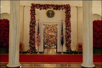 Viewed from the Cross Hall, the entrance to the Blue Room is decorated in red garland.