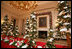 White tree lights twinkle in the shiny red and silver glass ornaments on the snow covered tabletop Christmas trees in the State Dinning Room.