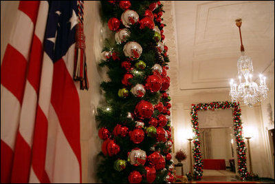 The doorways in the Cross Hall are outlined with boughs of evergreen garland and trimmed with glass ornaments, painted in red, green and silver.