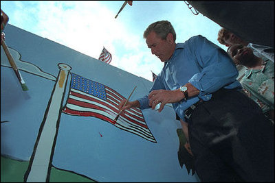As American flags throughout the neighborhood furled in the breeze, the President made a few waves of his own helping local children paint an American flag July 4, 2001.