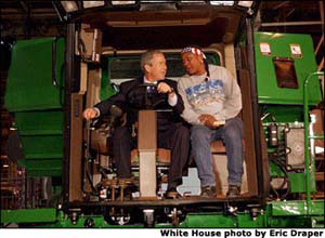 President George W. Bush talks with assembly worker Deborah Davis after starting up a combine with a gold-plated ignition key at John Deere Harvester Works in East Moline, Ill., Monday, Jan. 14, 2002. "I'm confident in the American farmer," said the President, addressing about 1500 employees and supporters. "I know the American farmer is more efficient, and can raise more crop than anybody, anywhere in the world." White House photo by Eric Draper.