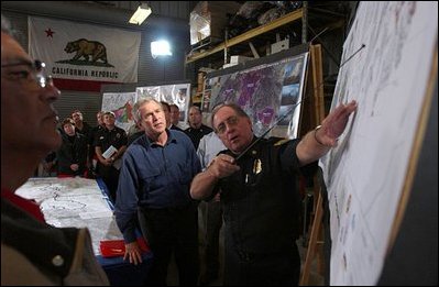 President Bush is a briefed on the wildfires in El Cajon, Calif., Nov. 4, 2003. "I met a lady at the airport when I landed at Miramar," said the President to the press. "She's a Red Cross volunteer. She spent 100 hours this week helping people who hurt. And I suspect the citizens here who are -- at the darkest moments will find light when a fellow citizen loves them. And the response, as I understand in this neighborhood, had been terrific, where people have come together and they want to help their -- help their fellow citizens."