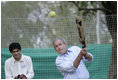 President George W. Bush watches his hit during a cricket clinic with Pakistani youth from the Schola Nova school and the Islamabad College for Boys, Saturday, March 4, 2006, at the Raphel Memorial Gardens on the grounds of the U.S. Embassy in Islamabad, Pakistan.