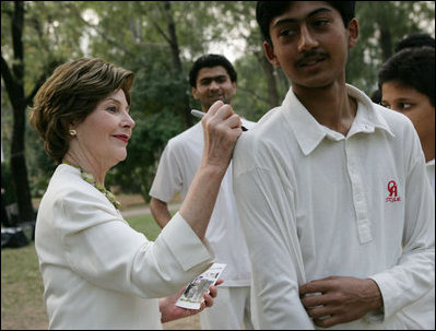 Mrs. Laura Bush signs the jerseys of students from the Schola Nova school and the Islamabad College for Boys, Saturday, March 4, 2006, who participated in a cricket clinic with President George W. Bush at the Raphel Memorial Gardens on the grounds of the U.S. Embassy in Islamabad, Pakistan.