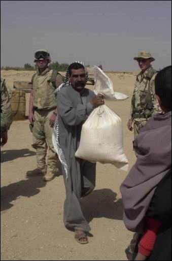 A man carries a bag of rice provided by an international relief agency and delivered by soldiers from the 422nd Civil Affairs Battalion in a village near the city of Najaf in central Iraq on April 04, 2003. (DoD photo by Staff Sgt. Kevin P. Bell, U.S. Army.) 