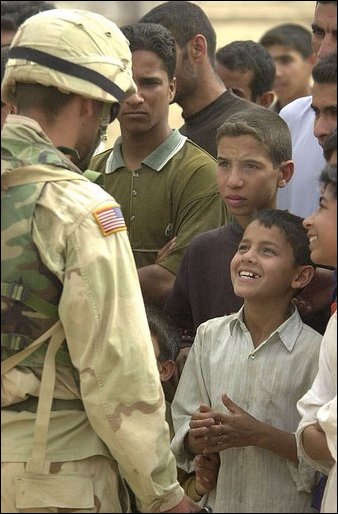 An Iraqi boy smiles as he talks with a U.S. Army soldier during an effort to distribute food and water to Iraqi citizens in need.