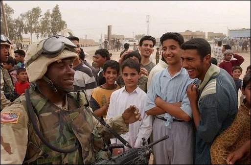 Iraqis share a laugh with a U.S. Army soldier during an effort to distribute food and water to Iraqi citizens in need.