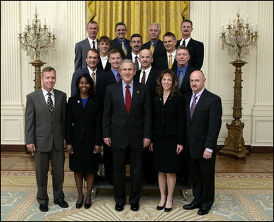 President George W. Bush stands with crew members of the Space Shuttle Discovery, the Space Shuttle Atlantis and the Space Station Expeditions 11, 12, and 13 Monday, Oct. 23, 2006, in the East Room of the White House. With the President in the front row, from left, are: Col. Steve Lindsey, Stephanie Wilson, Cmdr. Lisa Nowak, and Cmdr. Mark Kelly. Second row: Steven MacLean, Capt. Chris Ferguson, Col. Jeff Williams and Mike Fossum. Third row: Cmdr. Heidemarie Stefanyshyn-Piper, Cmdr. Dan Burbank and Dr. Piers Sellers. Top row: Capt. Brent Jett, Jr., Col. Bill McArthur, Jr. and Joe Tanner. 