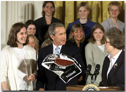 President George W. Bush holds a goalie glove with the
	team captain Brittny Ralph, left, and Chancellor Kathryn Martin
	of the Minnesota-Duluth 2001 NCAA Womens Hockey Champions
	Monday, June 25, 2001. WHITE HOUSE PHOTO BY PAUL MORSE