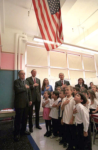 Accompanied by a chorus of little and big voices, President Bush says "The Pledge of Allegiance," at an elementary school during his visit to New York Oct. 3. White House photo by Paul Morse.