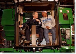 President George W. Bush talks with assembly worker Deborah Davis after starting up a combine with a gold-plated ignition key at John Deere Harvester Works in East Moline, Ill., Monday, Jan. 14, 2002. "I'm confident in the American farmer," said the President, addressing about 1500 employees and supporters. "I know the American farmer is more efficient, and can raise more crop than anybody, anywhere in the world."  White House photo by Eric Draper