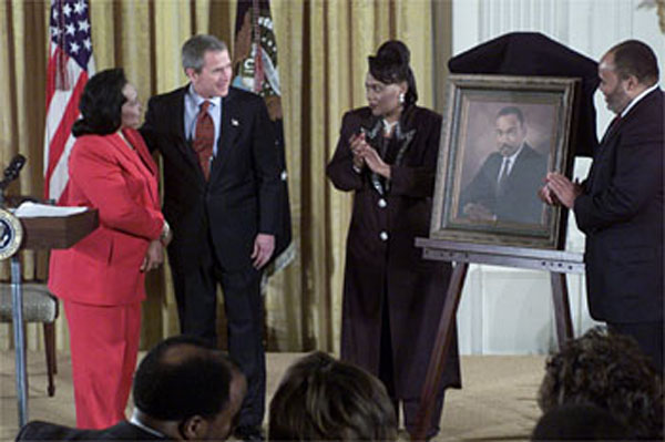 Proclaiming a holiday in honor of Martin Luther King, Jr., President George W. Bush receives a portrait of the civil rights leader from his wife and children in the East Room Jan. 21, 2002. Photographed from left to right are Coretta Scott King, the President, Rev. Bernice King and Martin Luther King III. WHITE HOUSE PHOTO BY TINA HAGER.