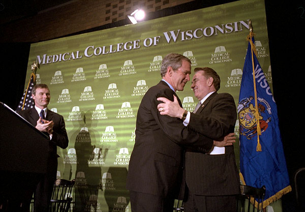 President George W. Bush embraces Secretary of Health and Human Services and former Wisconsin Governor Tommy Thompson after speaking about healthcare reform issues at the Medical College of Wisconsin in Milwaukee, Wis., February 11, 2002. Wisconsin's current governor Scott McCallum is also pictured. White House photo by Paul Morse.