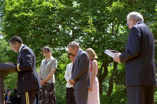 Led by Army Chaplain David Hicks, President George W. Bush prays with the family and friend of two recipients of the medal of honor during posthumous ceremony in the Rose Garden May 1, 2002. White House photo by Tina Hager.