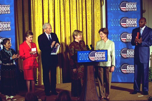 Laura Bush welcomes Ludmila Putina, wife of Vladimir Putin, President of the Russian Federation, to the Second Annual National Book Festival Saturday, October 12, 2002 in the East Room of the White House. Standing with the First Ladies on stage are, left to right, Native American poet Lucy Tapahoso, writer Mary Higgins Clark , Librarian of Congress Director James Billington and NBA player Jerry Stackhouse. White House photo by Susan Sterner.