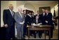 President George W. Bush signs the Sudan Peace Act in the Roosevelt Room at the White House, Oct. 21, 2002. Standing with the President are lawmakers and the Secretary of State Colin Powell, far left, and former Senator and special envoy for peace to the Sudan John Danforth, second from right. 