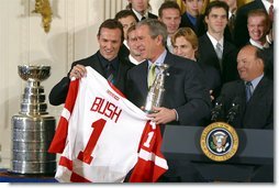 Receiving a jersey from team captain Steve Yzerman, President George W. Bush welcomes the Detroit Red Wings, winners of the NHL 2002 Stanley Cup Championship, to the East Room of the White House Friday, Nov. 8.  White House photo by Paul Morse