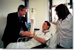 President George W. Bush shakes hands with Army SFC Thomas Douglas of Fayetteville, N.C., after presenting him with the Purple Heart at Walter Reed Army Medical Center in Washington, D.C., Friday, April 11, 2003. Also pictured is Mr. Douglas' wife, Donna Douglas.  White House photo by Eric Draper