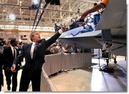 President George W. Bush reaches for a cap to sign after speaking at the Boeing F-18 Production Facility in St. Louis, Mo., Wednesday, April 16, 2003.  White House photo by Eric Draper