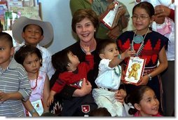 Children at the Kayenta Indian Health Service Clinic crowd around Laura Bush after she reads to them and tours the facility in Kayenta, Arizona, May 8, 2003.  White House photo by Susan Sterner
