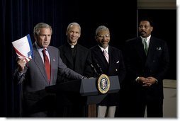 Holding up a book about his Faith-Based Initiatives, President George W. Bush talks with urban leaders in the Eisenhower Executive Office Building Wednesday, July 16, 2003. Standing behind the President are, from left, Rev. Bishop John Huston Ricard of Fla., Rev. Eugene F. Rivers III of Mass., and Tony Evans of Texas.  White House photo by Eric Draper