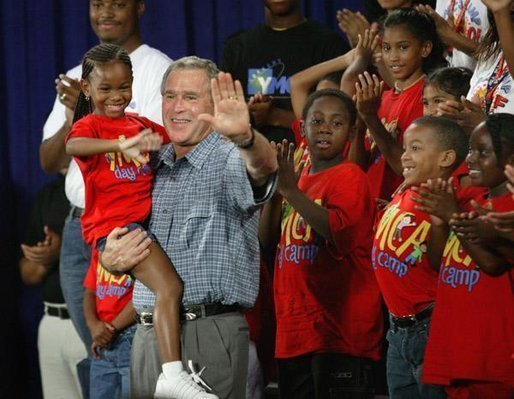 President George W. Bush joins children from Lakewest Family YMCA on stage after speaking on his Health and Fitness Initiative in Dallas, Texas, Friday, July 18, 2003. White House photo by Eric Draper