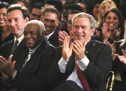 President George W. Bush applauds during the Celebration of Hispanic Heritage Month in the East Room, Thursday, Oct 2, 2003. Also pictured from left are, Tony Garza, U.S. Ambassador to Mexico and Pedro Knight, the husband of late singer Celia Cruz. White House photo by Eric Draper.