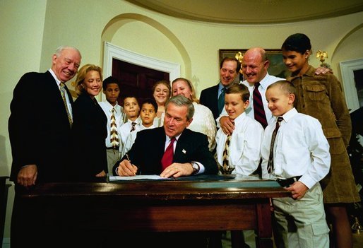 President George W. Bush signs the Adoption Promotion Act of 2003 in the Roosevelt Room December 2, 2003. Pictured with the President are the Chris and Diana Martin family. Their children are Katrina, 13, Ashley, 12, T.J., 11, Kyle, 10, Travis, 10, Dakota, 8, and Terrance, 7. Also pictured are Congressman James Oberstar, far left, Senator Mary Landrieu, and at back right, Congressman Dave Camp. White House photo by Eric Draper.
