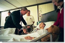 President George W. Bush speaks to U.S. Army Corporal James Rednour, of Ft. Campbell, Kentucky, after presenting him The Purple Heart for injuries Cpl. Rednour sustained while serving in Iraq. President Bush visited troops at Walter Reed Army Medical Center in Washinton, D.C., Thursday, December 18, 2003. Cpl. Rednour’s parents, Chuck and Cindy look on.  White House photo by Eric Draper