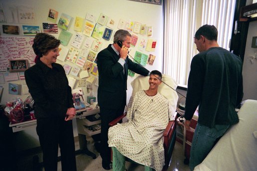President George W. Bush speaks to a relative of U.S. Army Sergeant First Class Joseph Briscoe, of Liberty, Texas, after presenting Sgt. Briscoe The Purple Heart for injuries he sustained while serving in Iraq. President Bush visited troops at Walter Reed Army Medical Center in Washinton, D.C., Thursday, December 18, 2003. Laura Bush and Sgt. Briscoe’s brother, Ira, look on. White House photo by Eric Draper