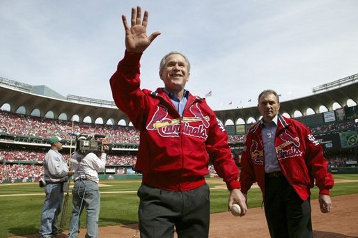After throwing out the first pitch during the St. Louis Cardinals’ season opener against the Milwaukee Brewers, President George W. Bush waves to the crowd as he walks off the field holding his pitched baseball Monday, April 5, 2004. White House photo by Eric Draper