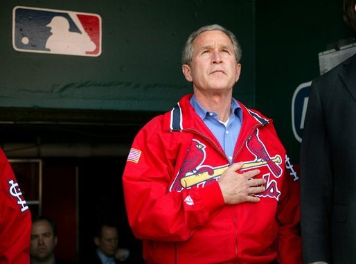 President George W. Bush stands for the playing of the national anthem in the St. Louis Cardinal’s dugout during their season opener against the Milwaukee Brewers Monday, April 5, 2004. As part of the opening ceremonies for the 2004 baseball season, President Bush threw out the first pitch. White House photo by Eric Draper