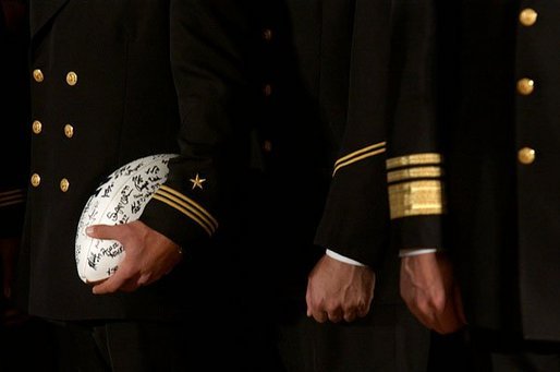 Signed by the entire team as a gift for the President, a football is tucked under the arm of a member of the U.S. Naval Academy football team during the presentation of the Commander-In-Chief Trophy in the East Room Monday, April 19, 2004. White House photo by Tina Hager.