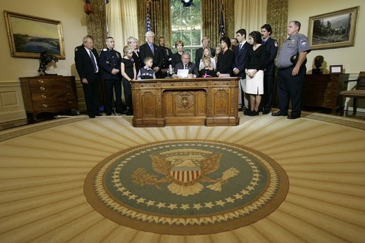President George W. Bush delivers a Live Radio Address surrounded by Mrs. Bush and families of victims of 911 in the Oval Office, Saturday, Sept. 11, 2004. White House photo by Eric Draper