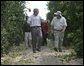 President George W. Bush walks with Pat McKenna through a hurricane-battered orange grove in Lake Wales, Fla., Wednesday, Sept. 29, 2004. Located in the heart of Florida's citrus country, almost half of the McKenna brothers' orange grove was destroyed by the hurricanes. White House photo by Eric Draper.