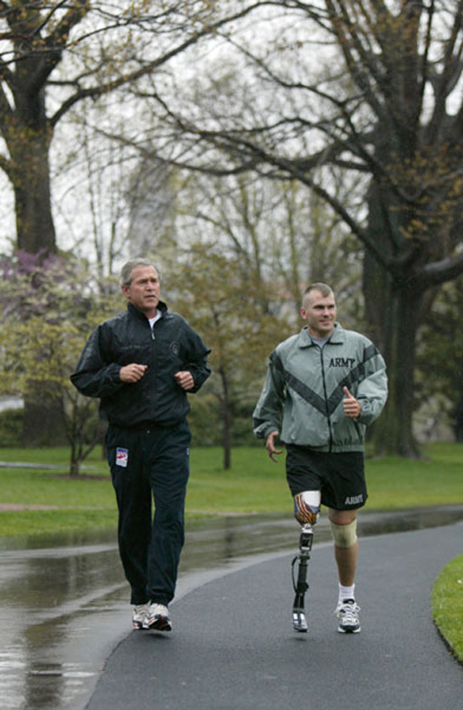 President George W. Bush runs with U.S. Army Staff Sergeant Michael McNaughton, of Denham Springs, La., on the South Lawn April 14, 2004. The two met Jan. 17, 2003, at Walter Reed Army Medical Center, where SSgt. McNaughton was recovering from wounds sustained in Afghanistan. The President wished SSgt. McNaughton a speedy recovery so that they might run together in the future. White House photo by Eric Draper.